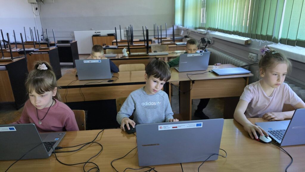 Uczniowie pracują przy laptopach podczas zajęć informatycznych, rozwijając umiejętności cyfrowe w ramach projektu EduAkcja.