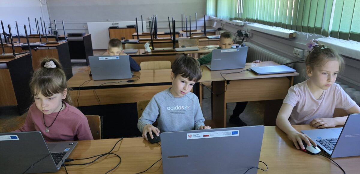 Uczniowie pracują przy laptopach podczas zajęć informatycznych, rozwijając umiejętności cyfrowe w ramach projektu EduAkcja.