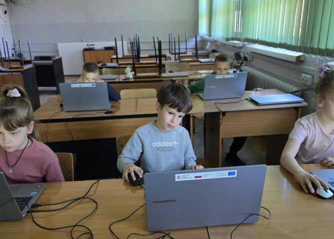 Uczniowie pracują przy laptopach podczas zajęć informatycznych, rozwijając umiejętności cyfrowe w ramach projektu EduAkcja.