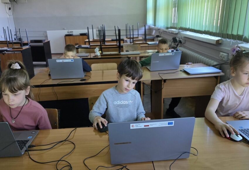 Uczniowie pracują przy laptopach podczas zajęć informatycznych, rozwijając umiejętności cyfrowe w ramach projektu EduAkcja.