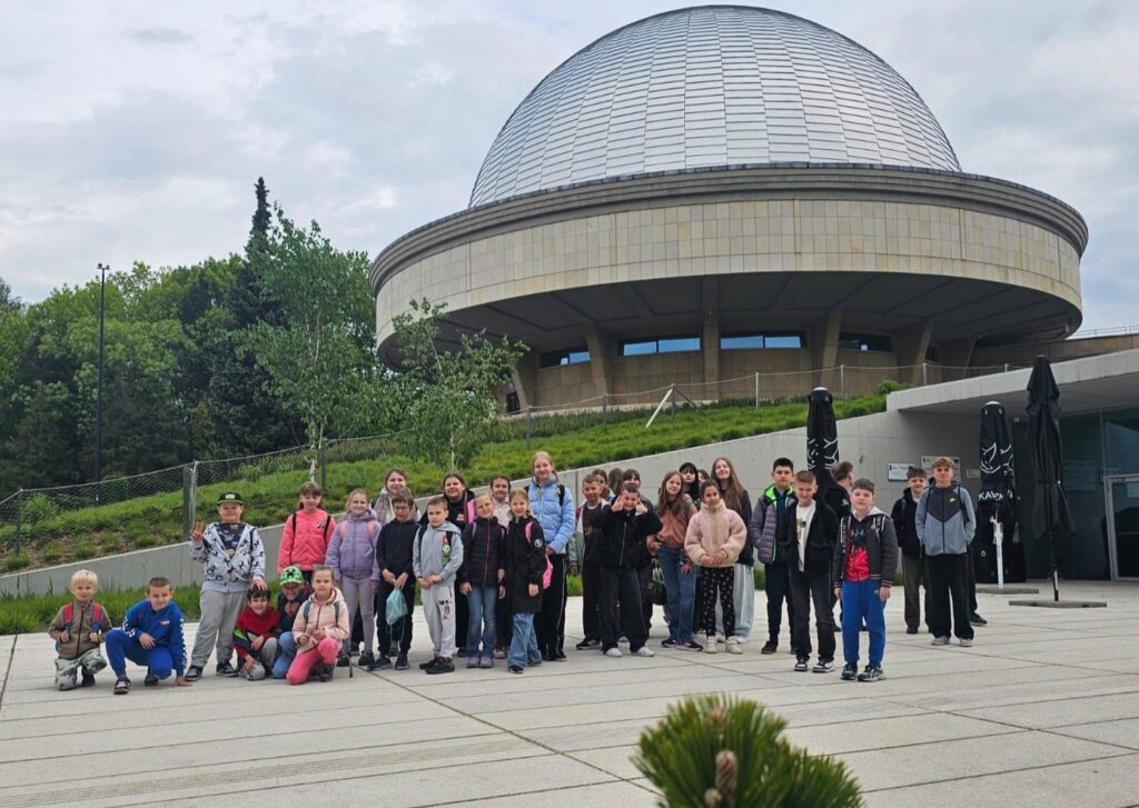 Uczniowie klas I–VIII podczas wycieczki do Planetarium – Śląskiego Parku Nauki w Chorzowie. Grupa stoi przed charakterystycznym budynkiem planetarium podczas realizacji projektu „EduAkcja”.