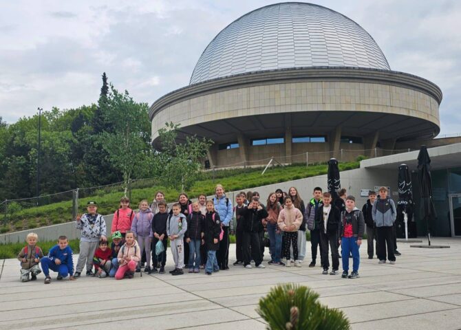 Uczniowie klas I–VIII podczas wycieczki do Planetarium – Śląskiego Parku Nauki w Chorzowie. Grupa stoi przed charakterystycznym budynkiem planetarium podczas realizacji projektu „EduAkcja”.