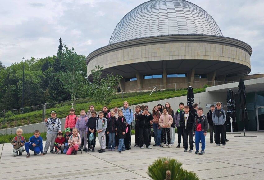 Uczniowie klas I–VIII podczas wycieczki do Planetarium – Śląskiego Parku Nauki w Chorzowie. Grupa stoi przed charakterystycznym budynkiem planetarium podczas realizacji projektu „EduAkcja”.