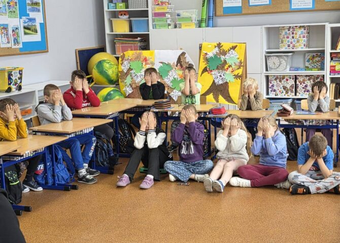 Uczniowie klas I–IV podczas warsztatów „Miej obraz osoby niewidomej”. Dzieci siedzą w sali lekcyjnej z zasłoniętymi oczami, uczestnicząc w ćwiczeniach pomagających zrozumieć codzienne wyzwania osób niewidomych.
