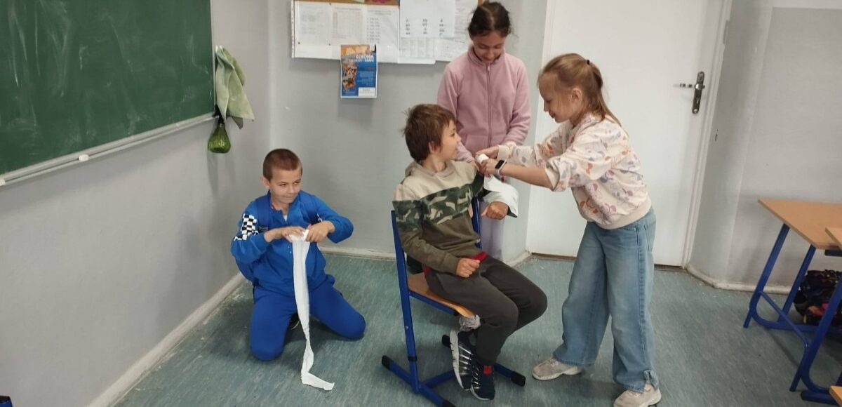Uczniowie podczas zajęć projektu „Na ratunek” ćwiczą udzielanie pierwszej pomocy – bandażowanie i usztywnianie ręki po urazach takich jak złamania, skręcenia i zwichnięcia.