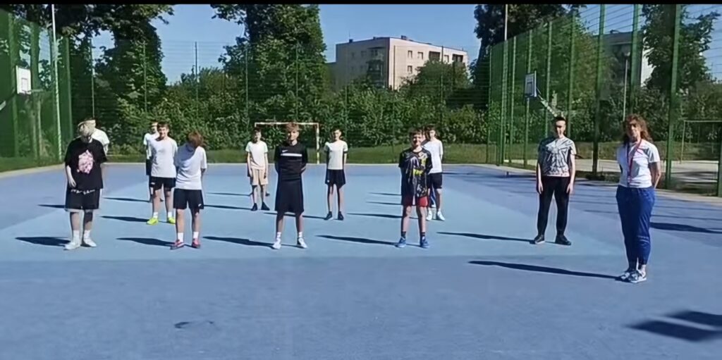 Uczniowie i nauczyciele naszej szkoły podczas akcji charytatywnej „#10pompek dla Milanka” na szkolnym boisku. Uczestnicy przygotowują się do wykonania sportowego wyzwania wspierającego zbiórkę dla chorego chłopca.