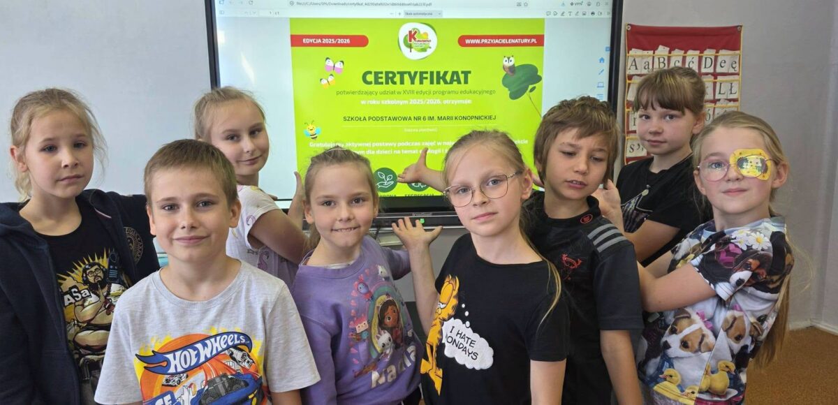 Uczniowie klas 1–2 prezentują certyfikat programu „Kubusiowi Przyjaciele Natury”, który szkoła otrzymała za udział w działaniach promujących zdrowy styl życia i edukację ekologiczną.