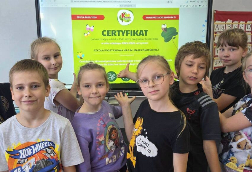 Uczniowie klas 1–2 prezentują certyfikat programu „Kubusiowi Przyjaciele Natury”, który szkoła otrzymała za udział w działaniach promujących zdrowy styl życia i edukację ekologiczną.